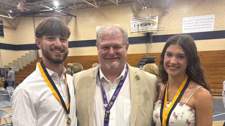 Jimmy Inman with two medal-winning students in a Covington High gym